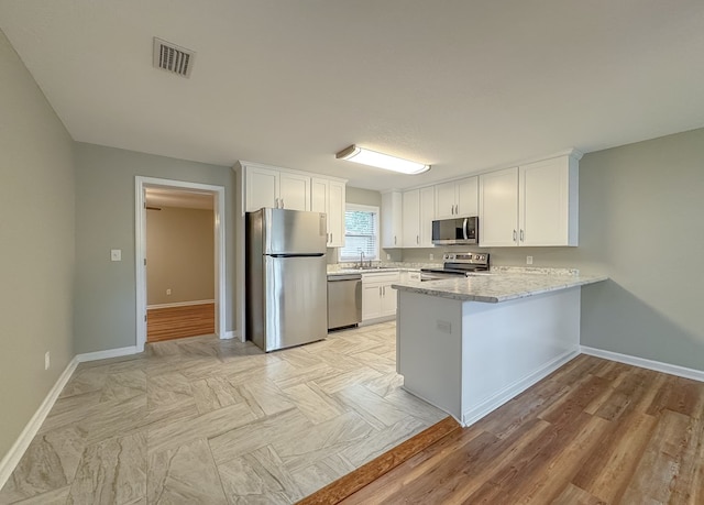 kitchen featuring kitchen peninsula, white cabinetry, light wood-type flooring, and appliances with stainless steel finishes