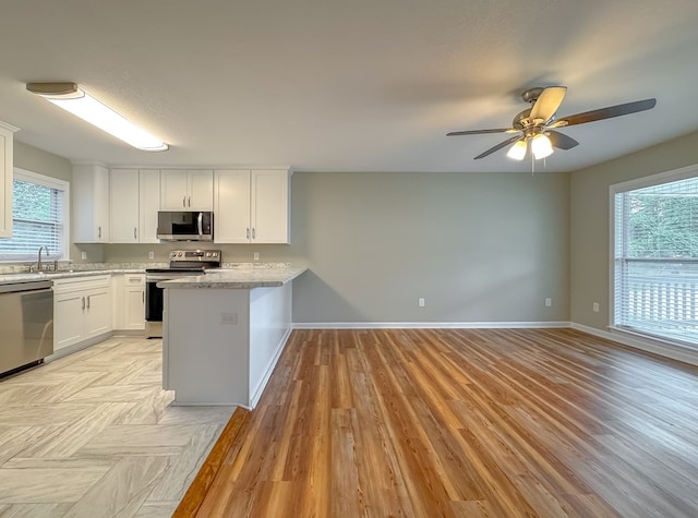 kitchen featuring white cabinets, a wealth of natural light, appliances with stainless steel finishes, and light hardwood / wood-style flooring