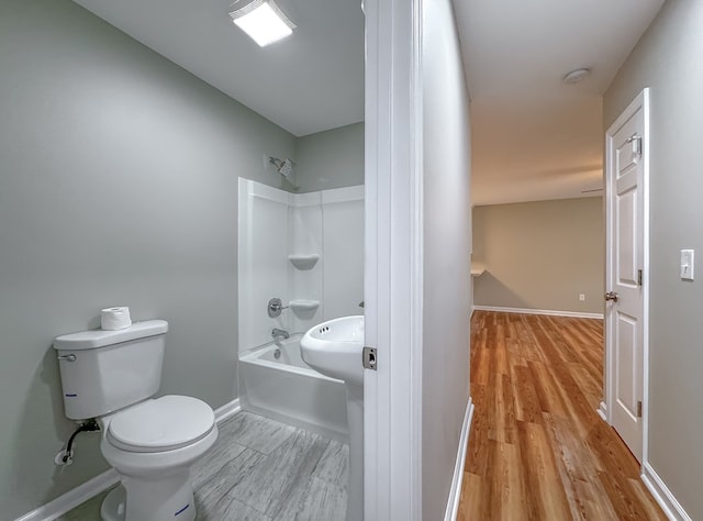 bathroom with hardwood / wood-style floors, shower / bath combination, and toilet