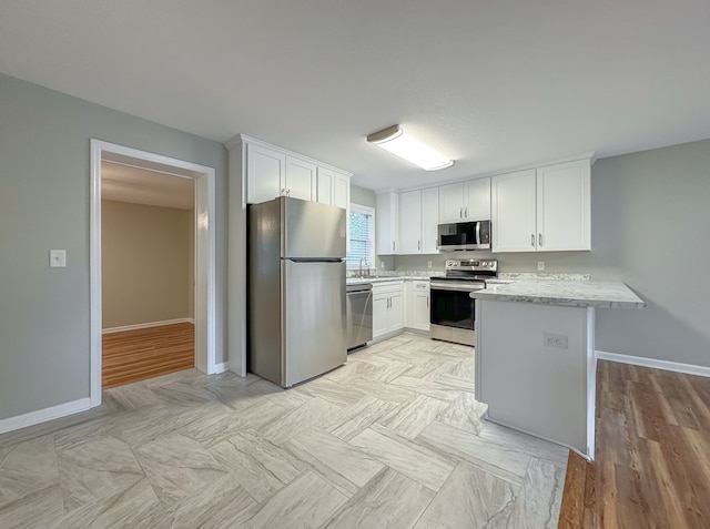 kitchen with kitchen peninsula, appliances with stainless steel finishes, light hardwood / wood-style floors, and white cabinetry