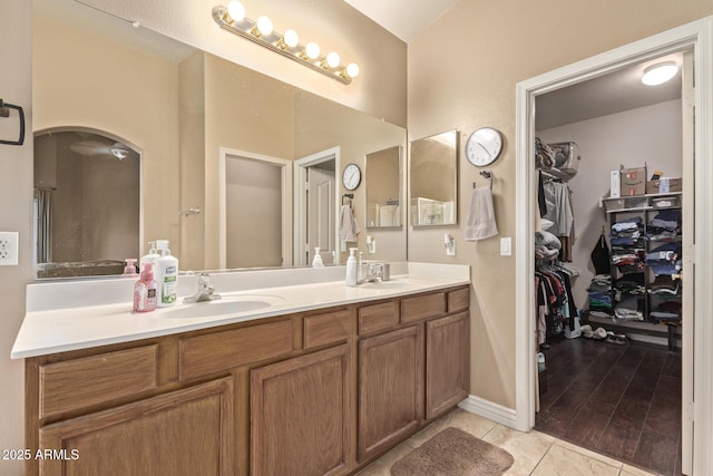 bathroom with double vanity, a spacious closet, tile patterned floors, and a sink