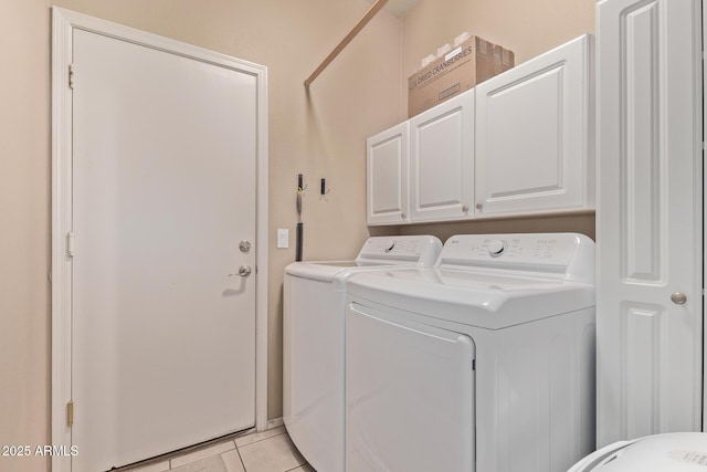 clothes washing area featuring washer and dryer, light tile patterned floors, and cabinet space