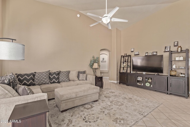 living room with light tile patterned floors, arched walkways, high vaulted ceiling, and a ceiling fan