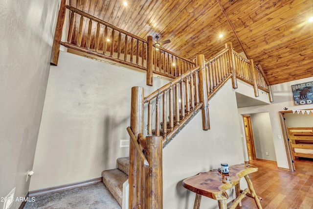 stairway featuring baseboards, a ceiling fan, wooden ceiling, wood finished floors, and high vaulted ceiling