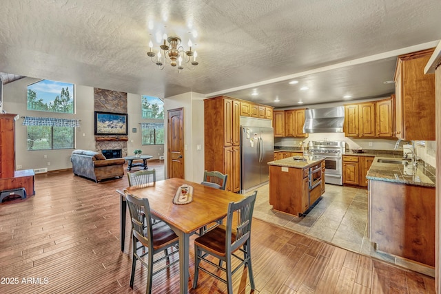 dining space with a fireplace, an inviting chandelier, light wood-style floors, a textured ceiling, and baseboards