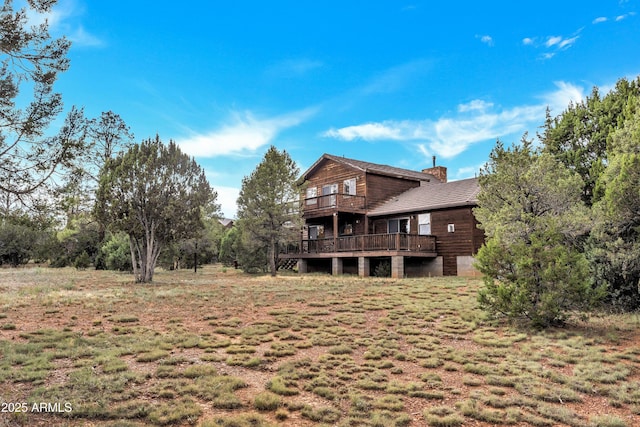 rear view of property featuring a chimney and a balcony