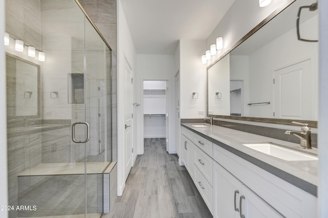 bathroom with wood-type flooring, a shower with door, and vanity