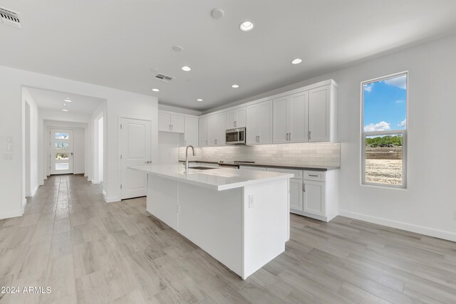 kitchen with an island with sink, a wealth of natural light, appliances with stainless steel finishes, and sink