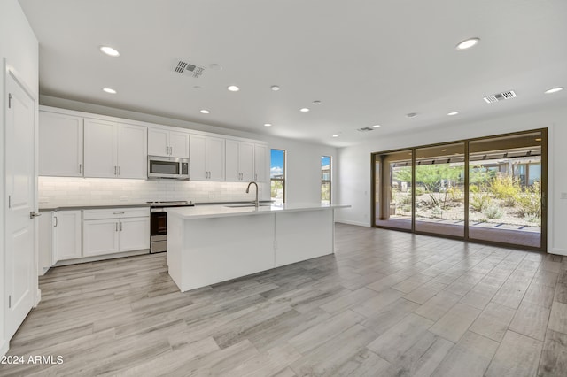 kitchen featuring white cabinets, sink, a kitchen island with sink, light hardwood / wood-style flooring, and stainless steel appliances