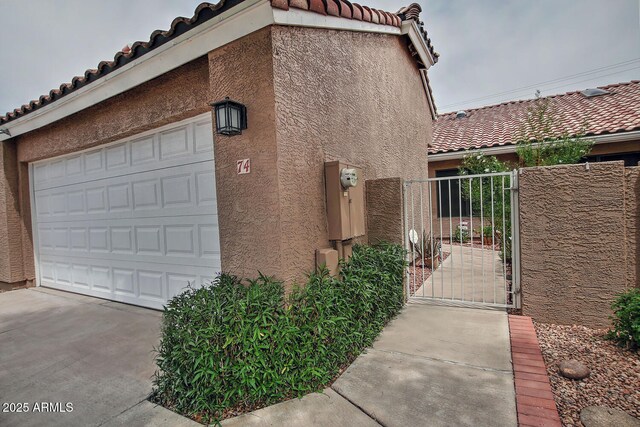 3510 E Hampton Ave Unit 74, Mesa, AZ 85204 - view of side of home with a tile roof, stucco siding, a gate, and a garage