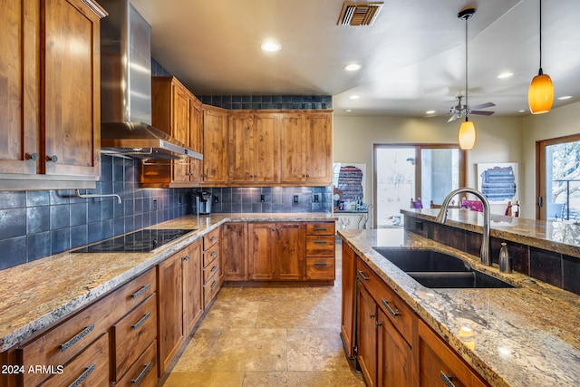 kitchen with black electric stovetop, sink, hanging light fixtures, wall chimney range hood, and ceiling fan