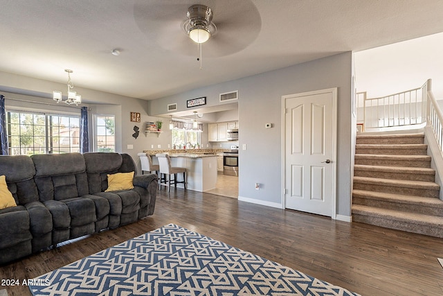 living room featuring ceiling fan with notable chandelier, dark hardwood / wood-style flooring, and a textured ceiling