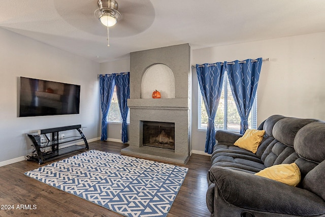 living room featuring dark hardwood / wood-style flooring, a large fireplace, ceiling fan, and a healthy amount of sunlight