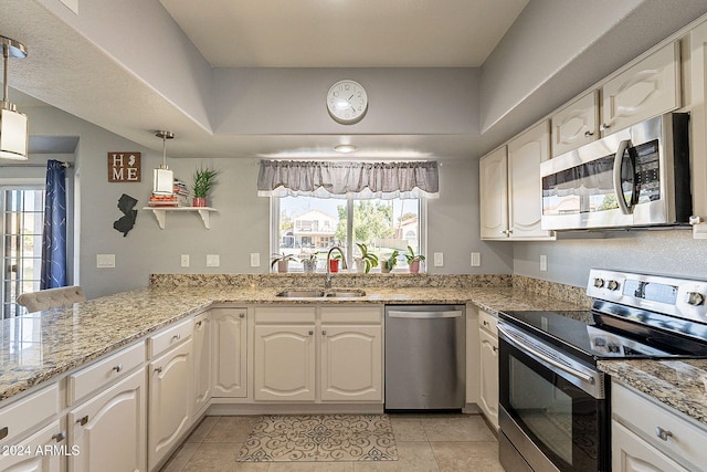 kitchen with hanging light fixtures, stainless steel appliances, white cabinets, and plenty of natural light