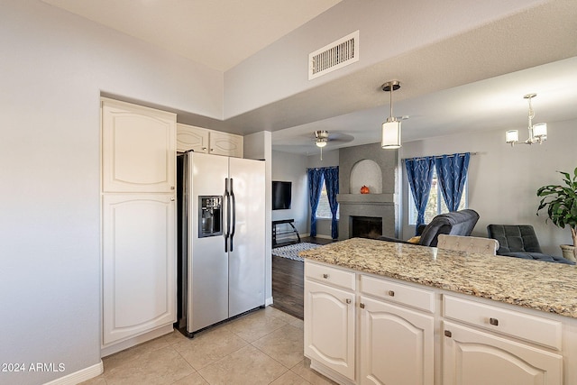 kitchen with a large fireplace, light tile patterned flooring, hanging light fixtures, and stainless steel refrigerator with ice dispenser