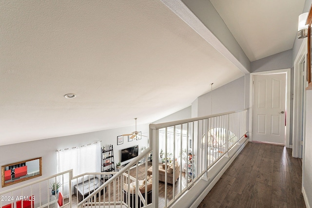 hall with dark hardwood / wood-style floors, lofted ceiling, and a chandelier