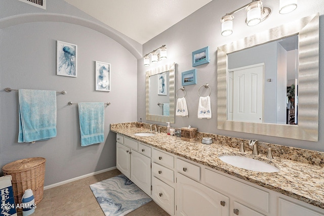 bathroom with tile patterned flooring, vanity, and lofted ceiling