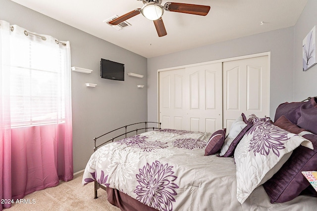 bedroom featuring ceiling fan, a closet, light carpet, and multiple windows