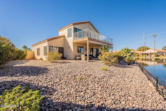 rear view of house featuring a balcony, a patio area, and a water view