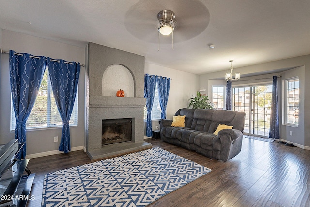 living room with dark hardwood / wood-style floors, a healthy amount of sunlight, ceiling fan with notable chandelier, and a fireplace