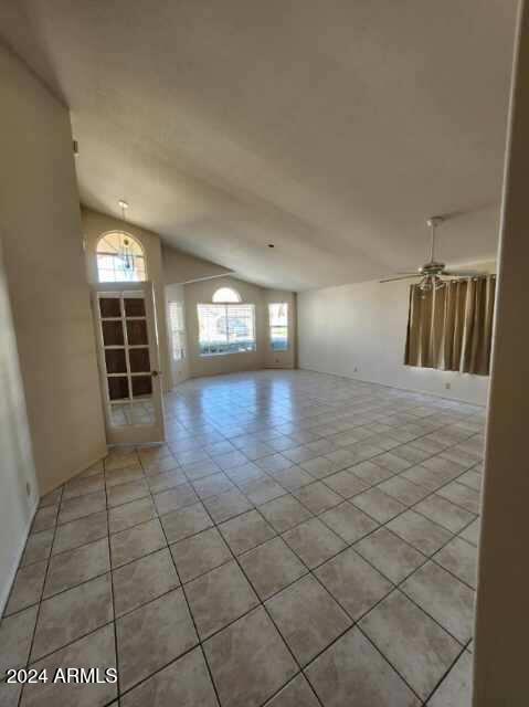 3853 W Calle Lejos, Glendale, AZ 85310 - unfurnished living room with vaulted ceiling, light tile patterned flooring, and a ceiling fan