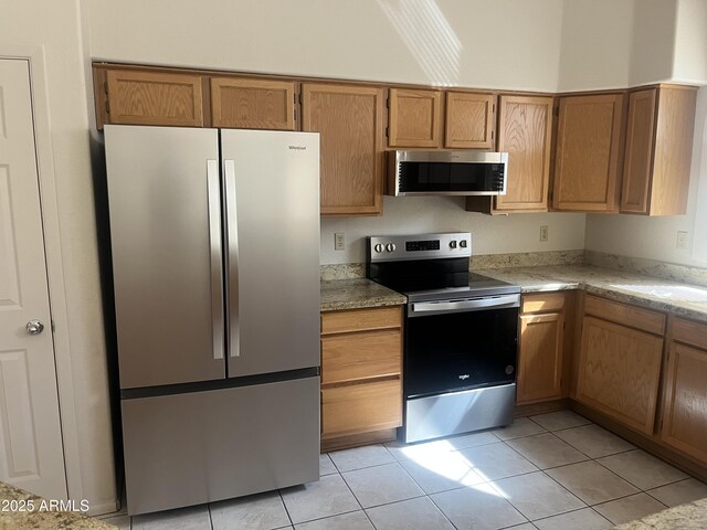 3853 W Calle Lejos, Glendale, AZ 85310 - kitchen featuring appliances with stainless steel finishes, light tile patterned floors, brown cabinets, and light stone counters