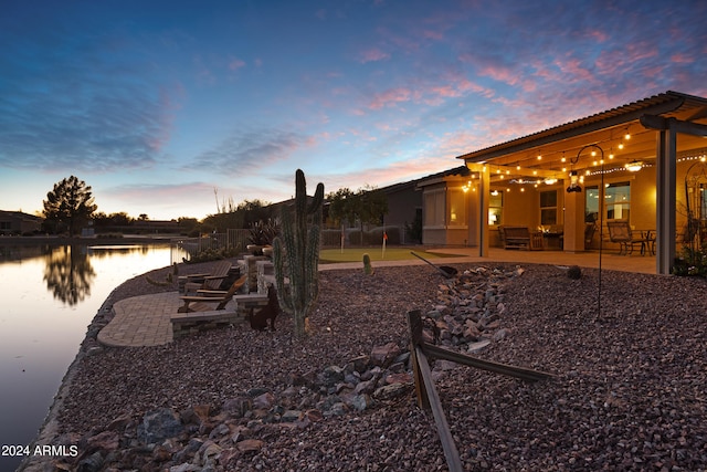 yard at dusk featuring a patio and a water view