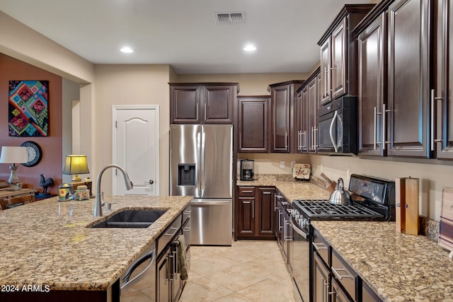 kitchen with light stone counters, dark brown cabinetry, sink, and appliances with stainless steel finishes