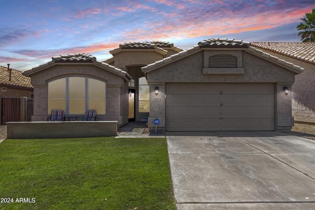 mediterranean / spanish-style home with an attached garage, driveway, a front lawn, and stucco siding