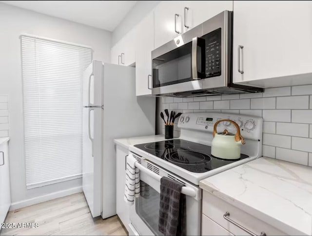 kitchen featuring white cabinetry, light stone counters, light hardwood / wood-style floors, decorative backsplash, and white electric stove