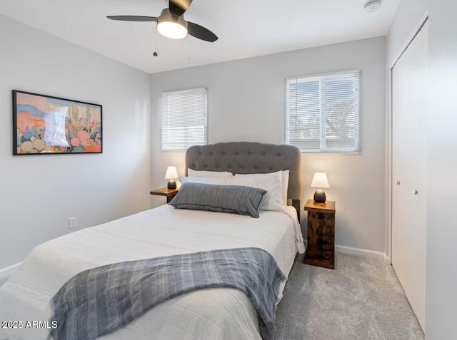 carpeted bedroom with ceiling fan, a closet, and multiple windows