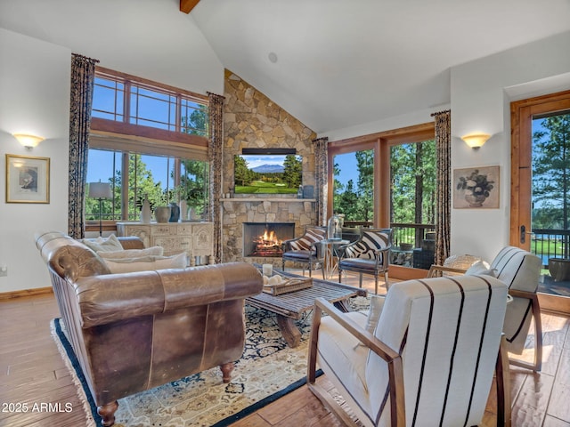 living room featuring high vaulted ceiling, baseboards, light wood-style floors, and a fireplace