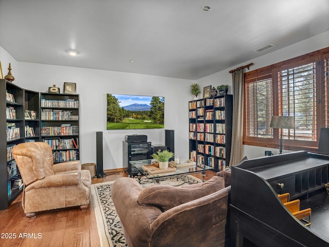 living room with baseboards, visible vents, and wood finished floors