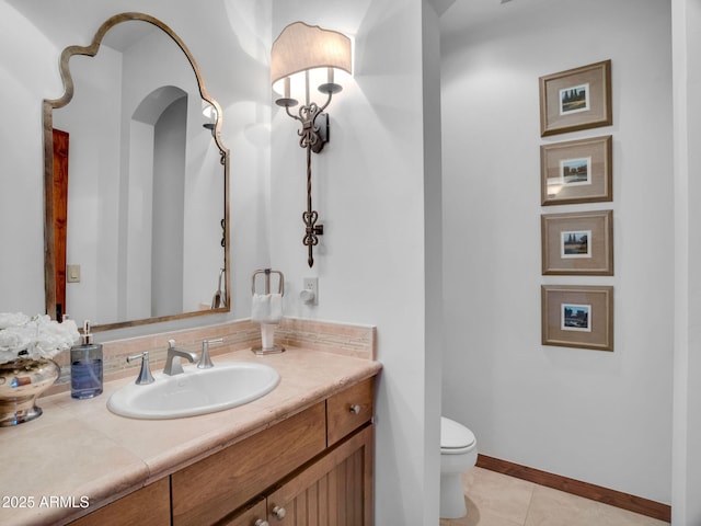 bathroom featuring toilet, tile patterned flooring, vanity, and baseboards