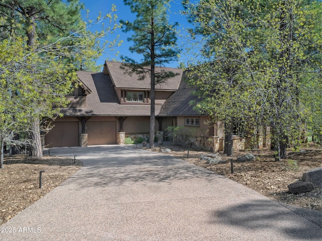 rustic home featuring driveway, stone siding, stucco siding, and a shingled roof