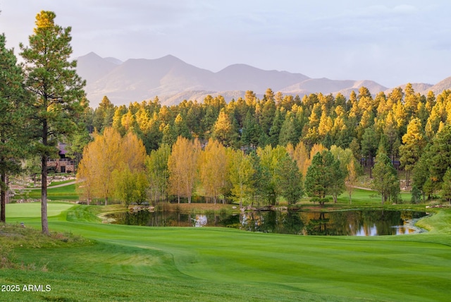 surrounding community with a water and mountain view, a yard, and golf course view