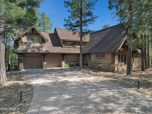 rustic home featuring driveway, stone siding, stucco siding, and a shingled roof