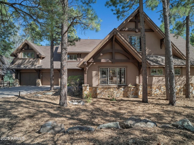 view of front of property featuring stucco siding, concrete driveway, an attached garage, and stone siding