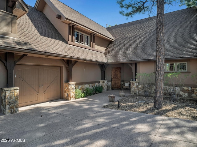 view of front of house featuring driveway, stone siding, roof with shingles, stucco siding, and a garage