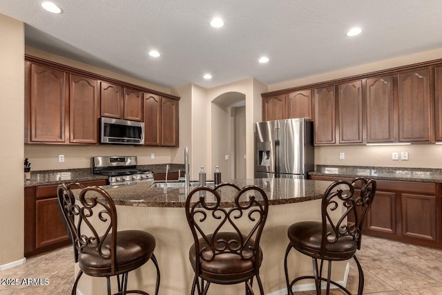3693 E Sparrow Pl, Chandler, AZ 85286 - kitchen with stainless steel appliances, a sink, a breakfast bar area, dark stone counters, and recessed lighting