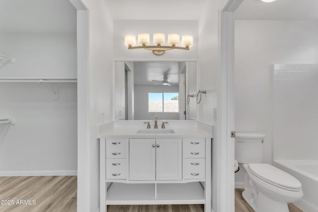 bathroom with wood-type flooring, vanity, toilet, and ceiling fan