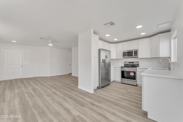 kitchen featuring sink, ceiling fan, light wood-type flooring, white cabinetry, and stainless steel appliances