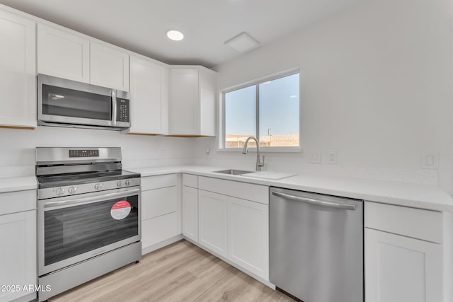 kitchen featuring white cabinets, appliances with stainless steel finishes, light hardwood / wood-style floors, and sink