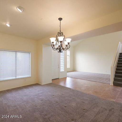 spare room featuring carpet and a notable chandelier