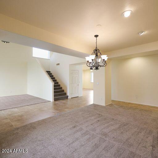 empty room with a healthy amount of sunlight, carpet floors, and a chandelier