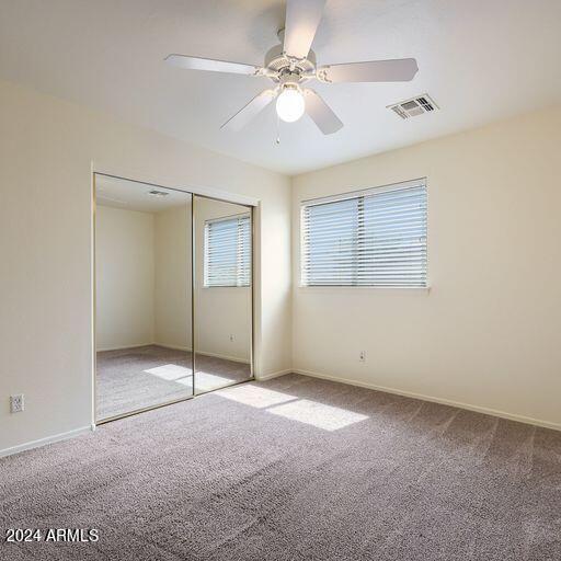 unfurnished bedroom featuring carpet, a closet, and ceiling fan