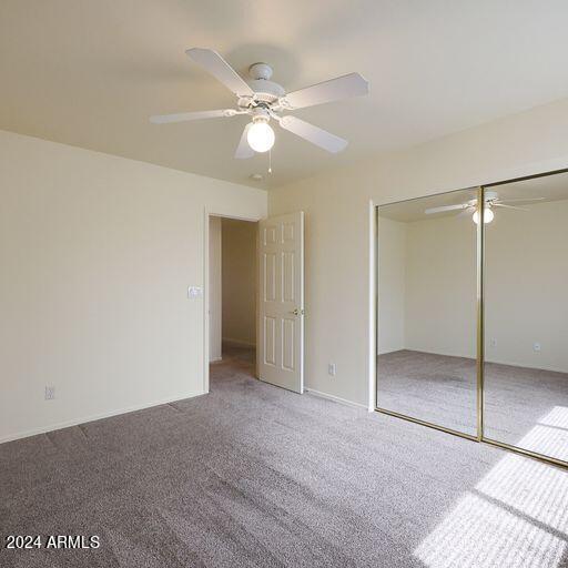 unfurnished bedroom with carpet, a closet, and ceiling fan