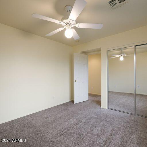 unfurnished bedroom with ceiling fan, a closet, and carpet