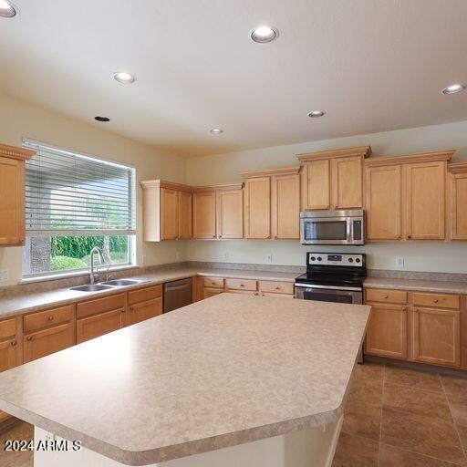 kitchen with dark tile patterned floors, sink, a kitchen island, and stainless steel appliances