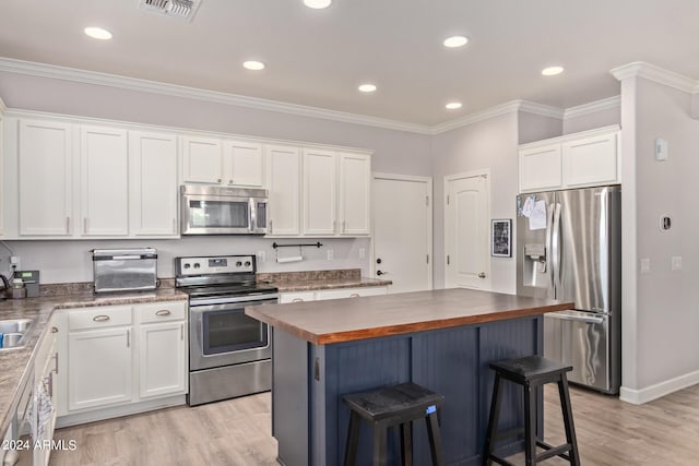 kitchen featuring butcher block counters, white cabinets, stainless steel appliances, and light wood-type flooring